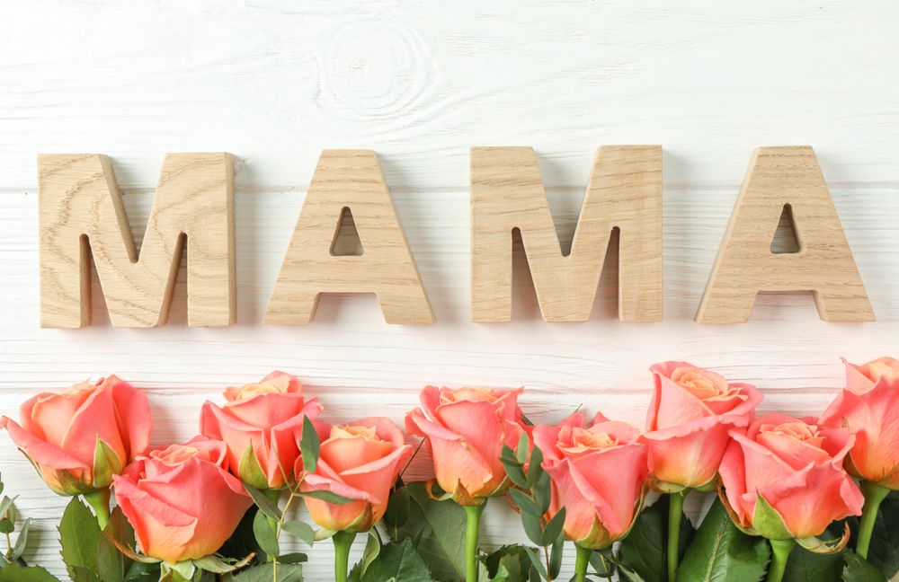 Beautiful orange roses and inscription Mama on bright background, space for text
