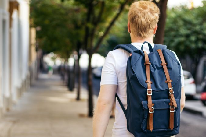 Latino man with albinism walking down the street with backpack