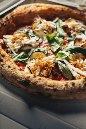 Two gourmet pizzas with toppings in delivery boxes on wooden table surface