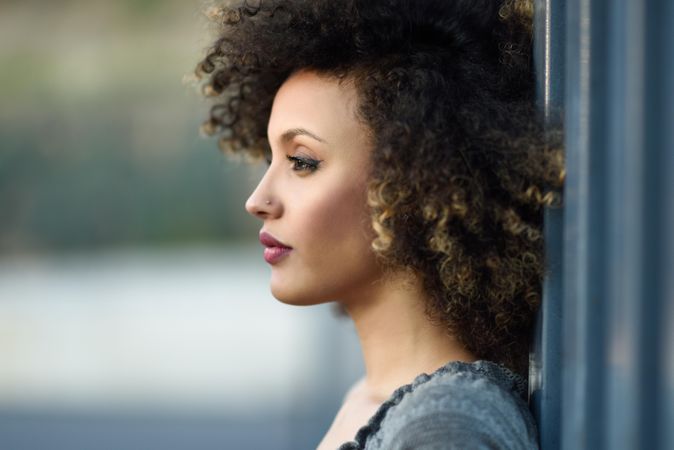 Profile of Black female looking away while leaning on wall outdoors