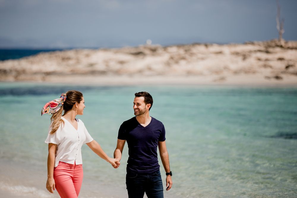 Happy couple walking on turquoise seashore in summer light