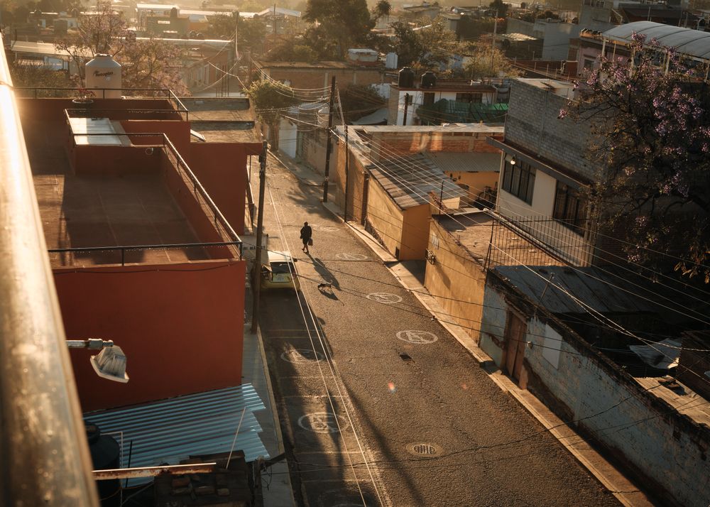 Single person with long shadow walking down quiet Mexican street