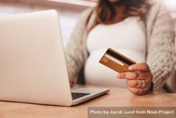 Close up shot of pregnant woman using laptop and holding credit card on table bYmGNb
