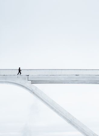 Person walking on light colored bridge
