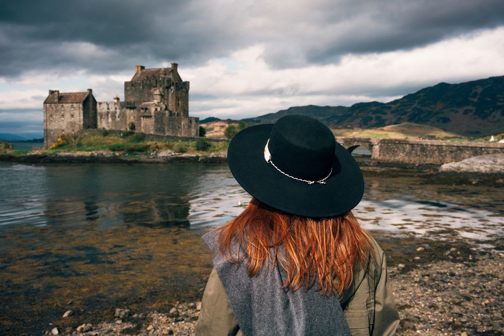 Smiling traveling woman contemplating castle landscape
