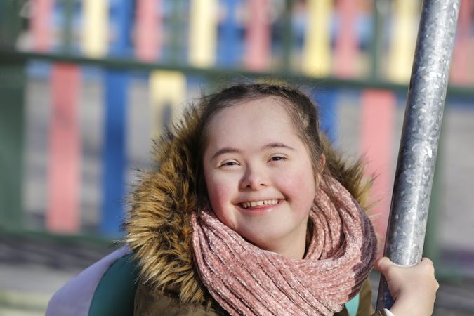 Happy girl wearing scarf and winter coat looking over her shoulder and smiling at camera