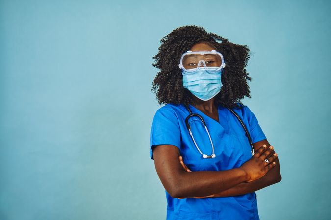 Black female medical professional wearing safety  face mask, protective eyewear and stethoscope