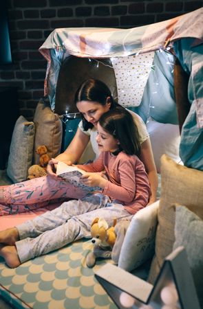 Mother and daughter reading a book in a diy tent