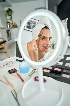 Reflection of smiling female doing makeup