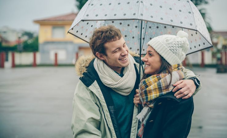 Laughing couple under umbrella together on cold day