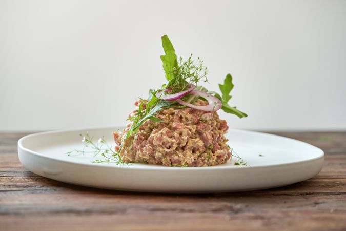 Plate with delicious steak tartar on wooden table
