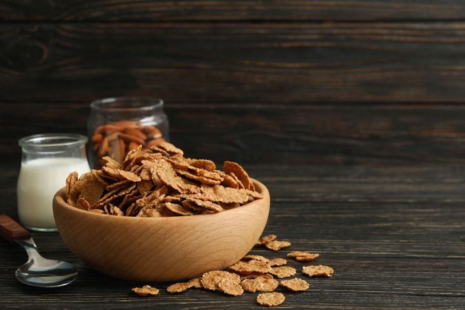 Muesli, milk, almond and spoon on wooden table