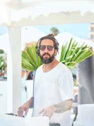 Ethnic man working on DJ controller on terrace in sunlight