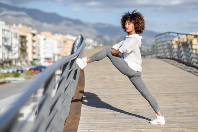 Woman warming up her legs on bridge before workout