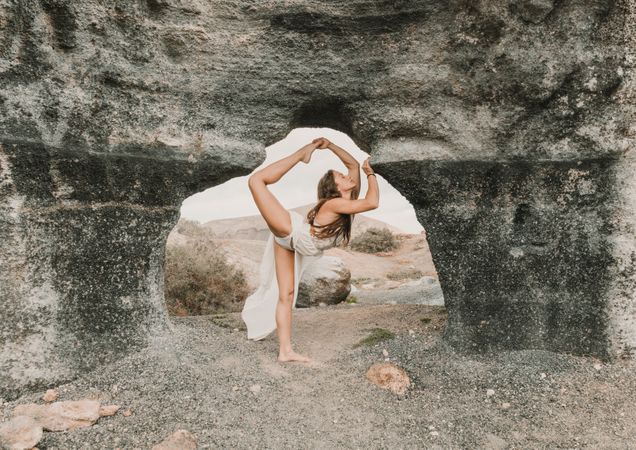 Flexible female doing split in stone arch