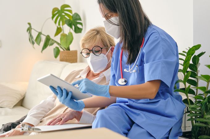 Crop physician interacting with patient while using tablet at home