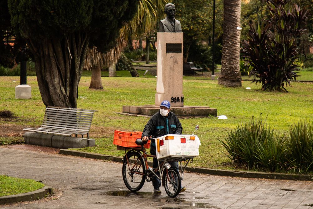 Man with facemask walking with a bike in a garden