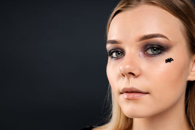 A woman with dark makeup for a Halloween party, with a bat