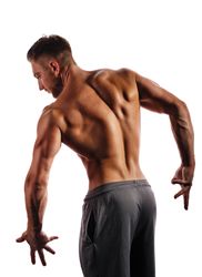 Bodybuilder’s back flexed practicing poses ahead of competition in light studio