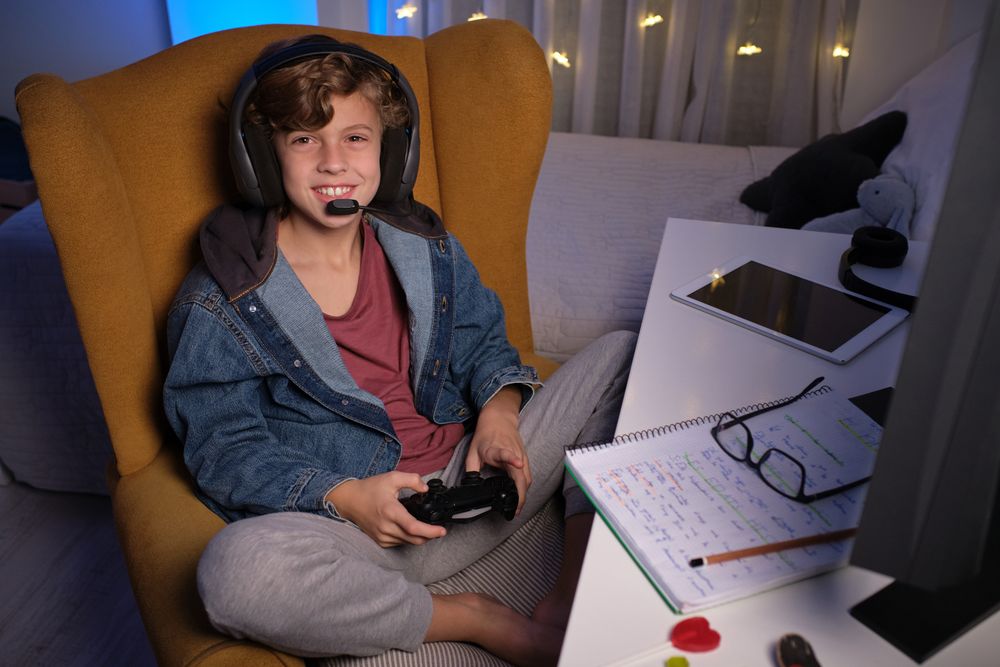 Child in headset enjoying game on computer in dark room