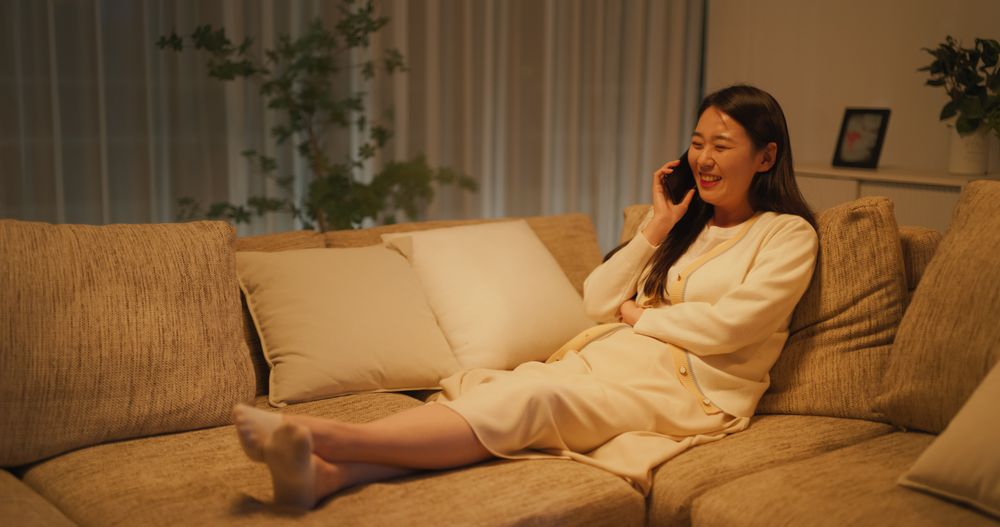 Relaxing on a Couch in the Evening in a Cozy Apartment, Smiling South Korean Woman