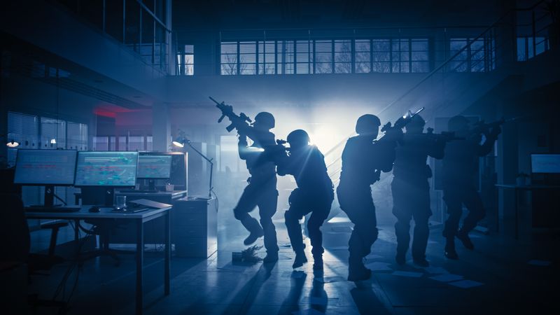 Masked Squad of Armed SWAT Police Officers Storm a Dark Seized Office Building with Desks and Computers.