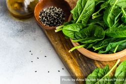 Wooden bowl of fresh spinach leaves on kitchen counter with space for text 0JGlap