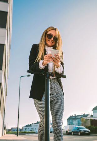 Businesswoman with electric scooter looking at the mobile