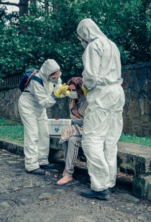 Doctors putting protective mask on woman infected with a virus
