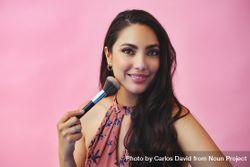Head shot of elegant Hispanic woman holding large make up brush 4BprM0