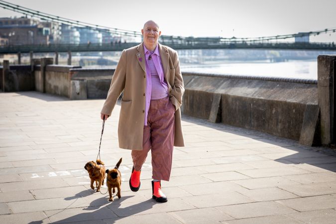 Mature man strolling by river with two small dogs