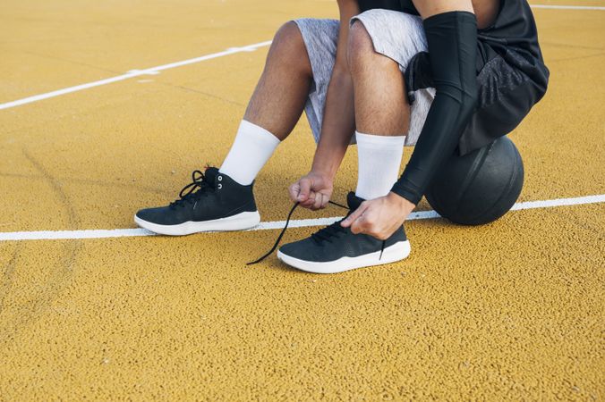 legs of crop Young man and ball playing on basketball court outdoor.