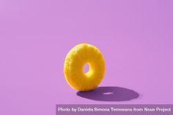 Pineapple ring balanced on purple background with shadow 43XZrb