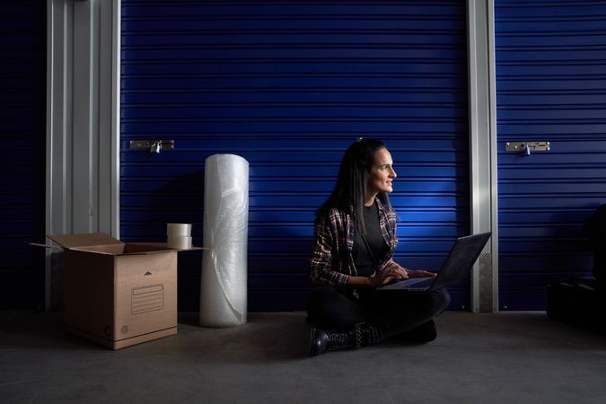 Woman browsing laptop near closed self storage