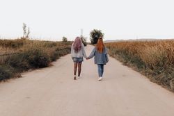 Strolling women holding hands in country