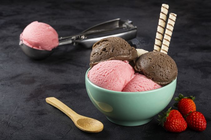 Bowl with Neapolitan ice cream on dark background.