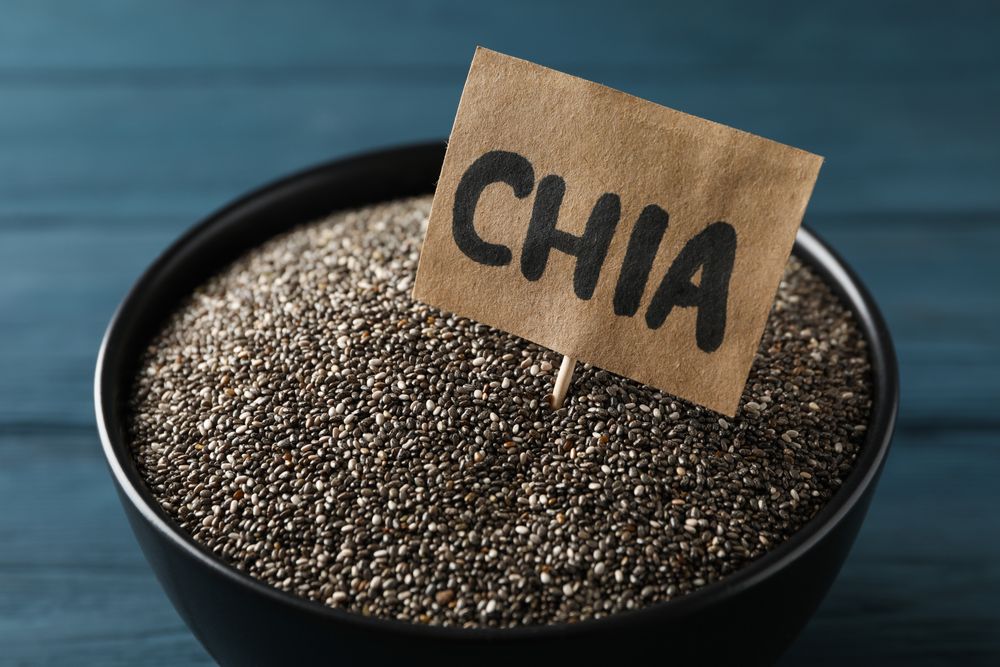 bowl and word Chia on wooden background, close up