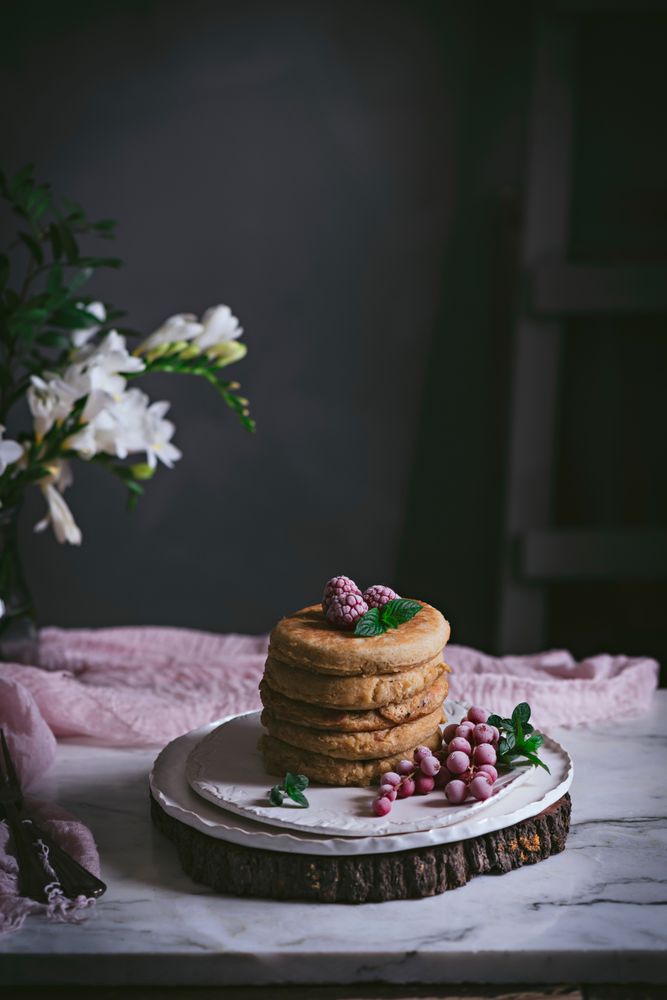 Pile of raspberry pancakes with honey on plate