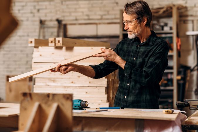 Mature man working in protective glasses in his carpentry studio