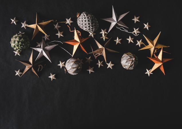 Flat-lay of colorful paper toy decorative stars, with pine cones and baubles, close together