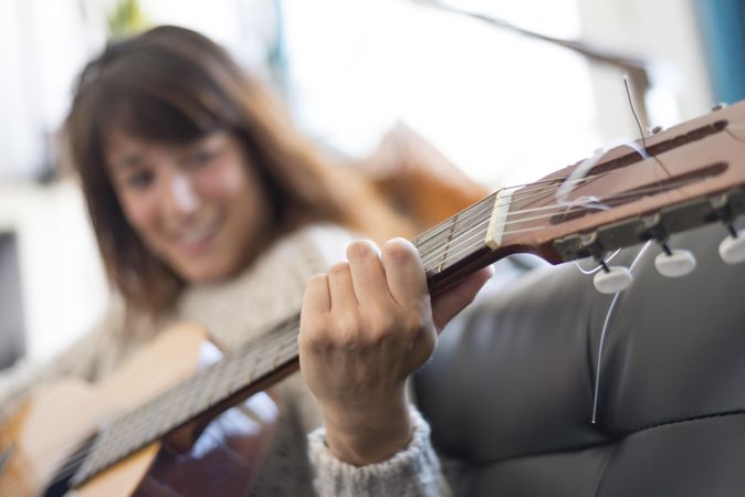 Female hand strumming acoustic guitar in bright loft