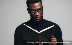 Black man looking at camera with a book in hand 433kP4