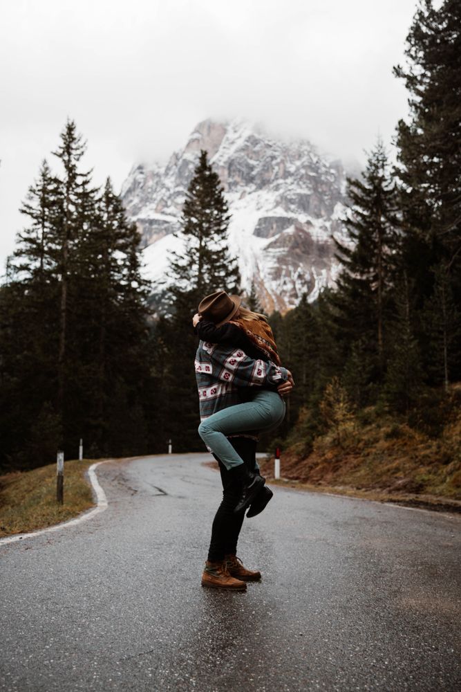 Casual resting couple standing in an embrace on route amid forest
