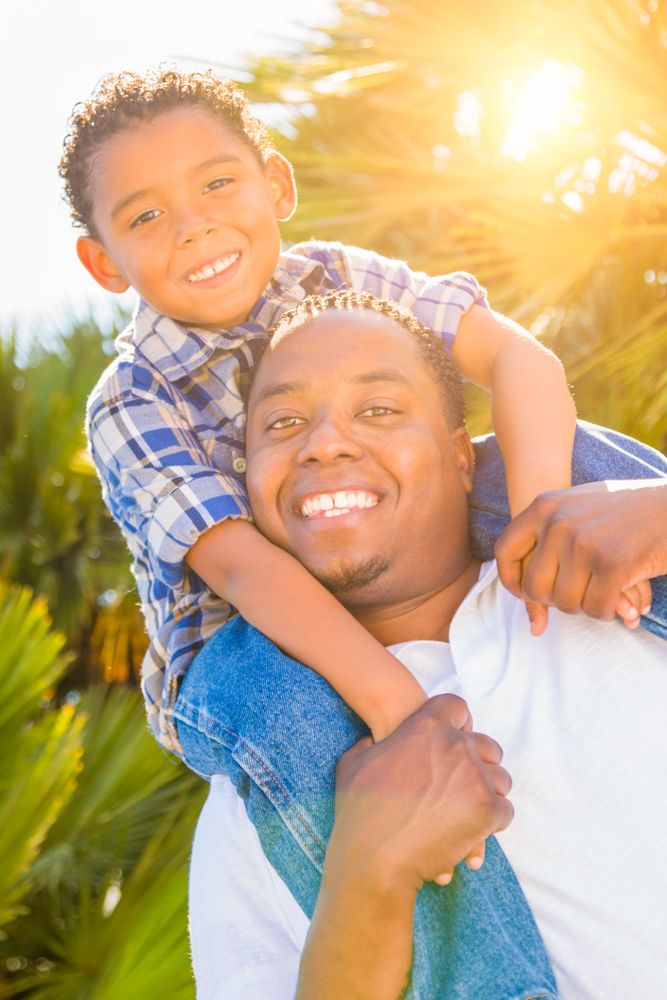 Son and Father Smiling Outdoors Together On Sunny Day