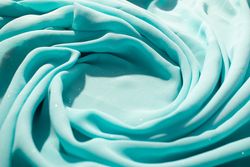 Spiral Twisted Turquoise wavy crumpled fabric with little sparkling dust and copy space in center, texture and  background.