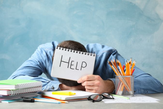 Man with head on desk overwhelmed with work