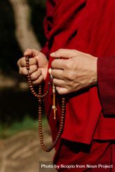 Cropped image of Buddhist monk holding prayer beads standing outdoor 4jzOz4