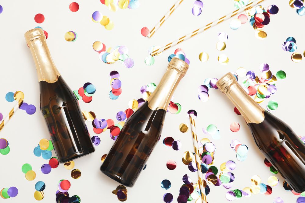 Composition with mini champagne bottles and glitter on light background, top view