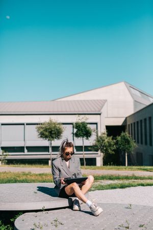 Stylish woman sitting and browsing tablet outside