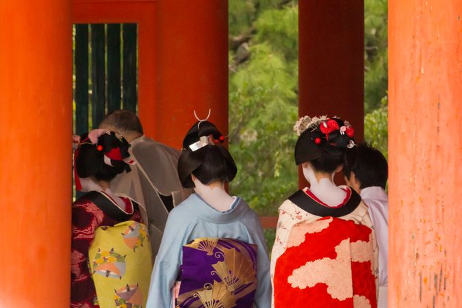 Back view of women in kimonos surrounded by red pillars